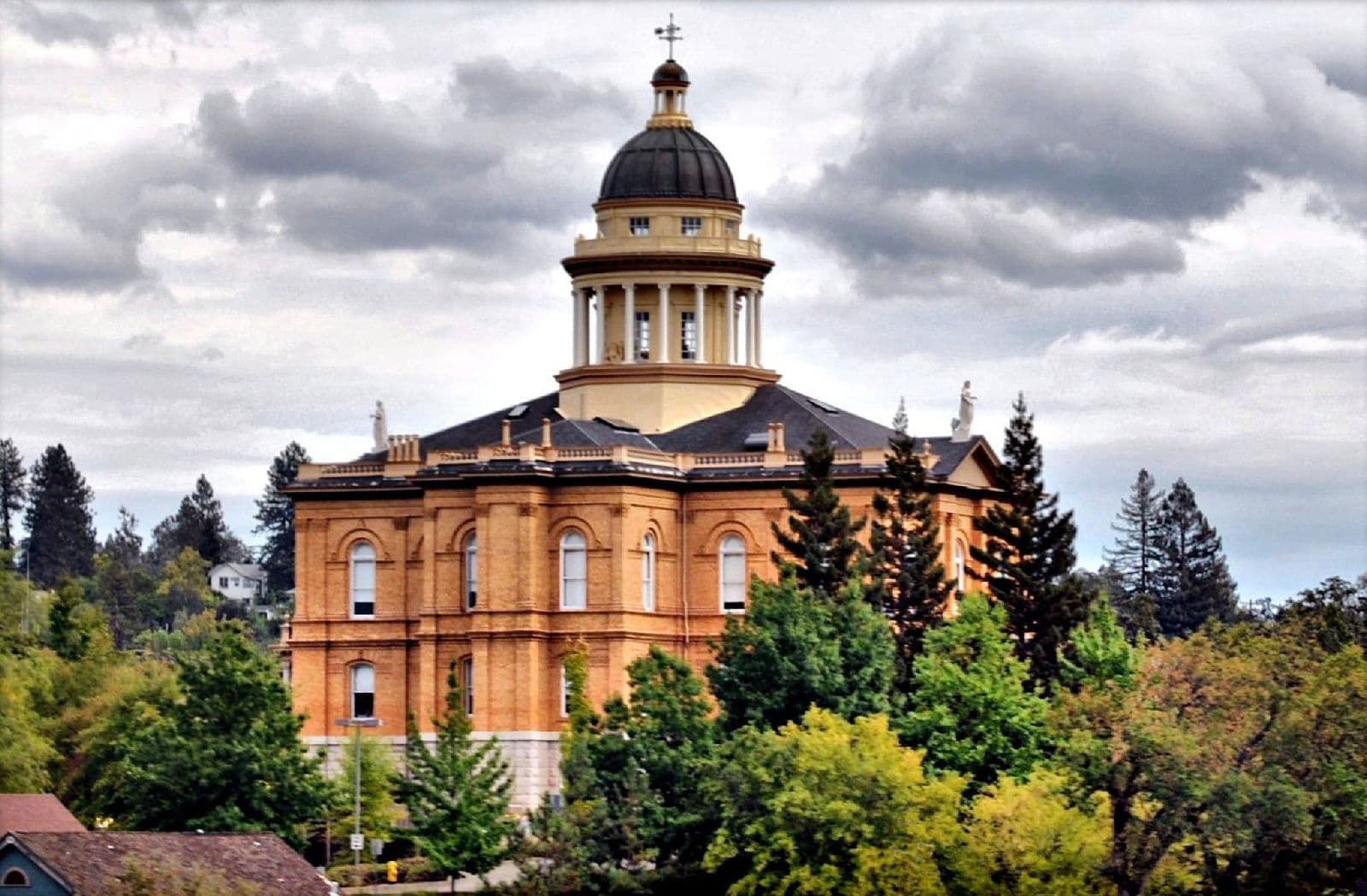 The historic Placer County Courthouse in Auburn, California, rising above a canopy of conifers and broadleaf trees