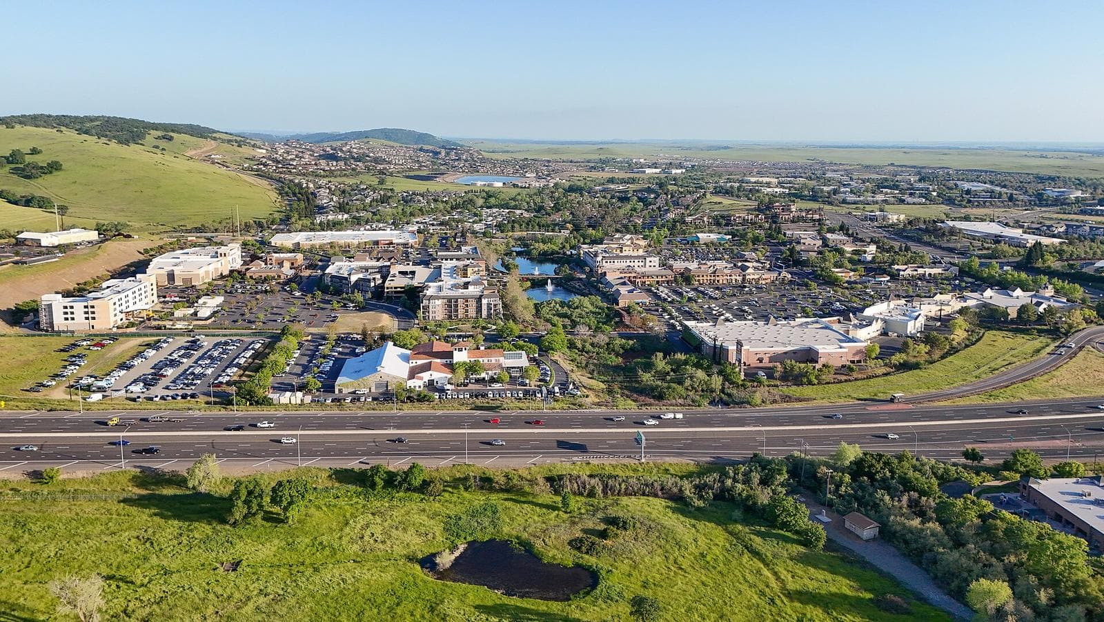 Aerial view of El Dorado Hills Town Center and Highway 50, with oak topped hills on the left and the flat Sacramento Valley on the horizon
